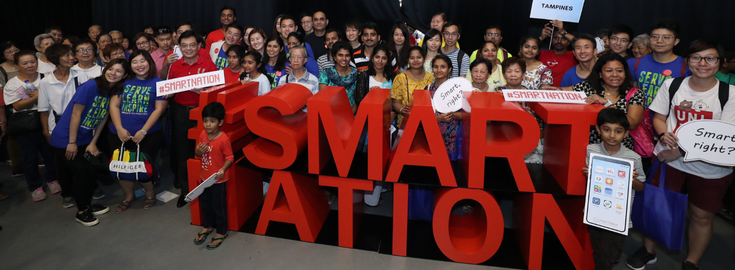 Large group with red "#SMARTNATION" letters. People hold signs like "Tampines" and "Smart, right?".